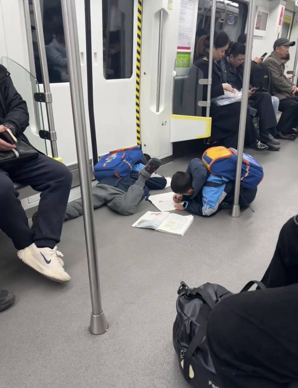 两名小孩哥一上地铁就滑铲倒地，趴地上写作业，引来数万网友共鸣：这才是童年的样子